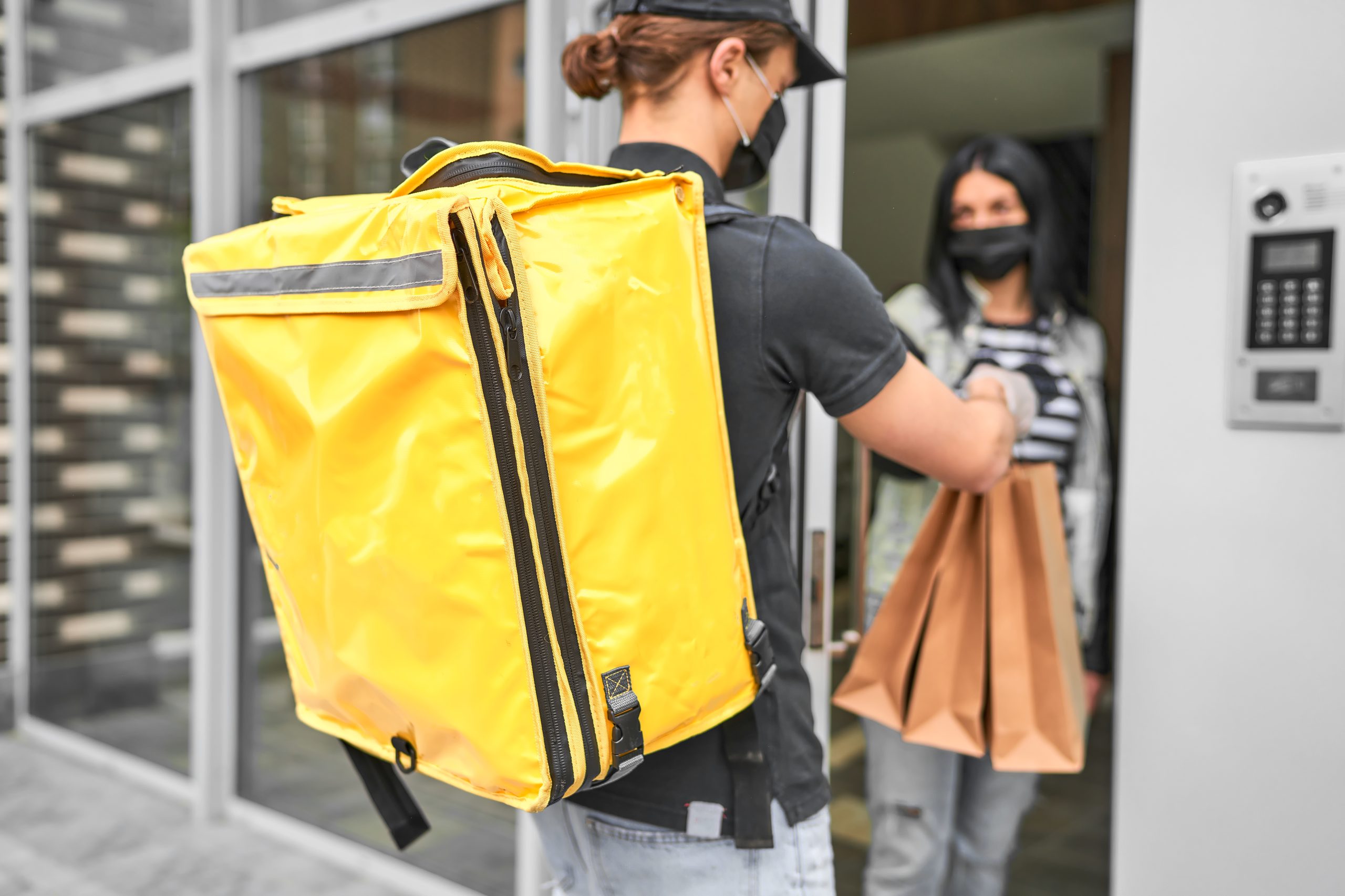 A courier with a backpack and food delivered an online order to